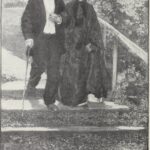 An elderly couple walking together through a green park on a sunny day
