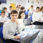 Students with laptops studying together in a bright classroom
