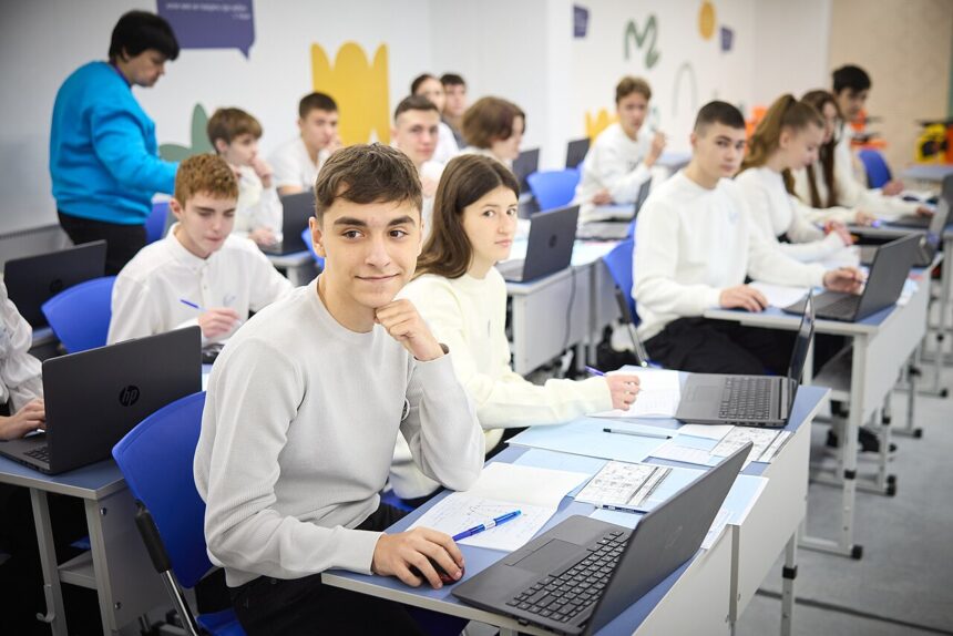 Students with laptops studying together in a bright classroom